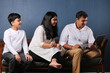 © Ojas - Indian family sitting on sofa and using laptop watching movie or surfing internet.