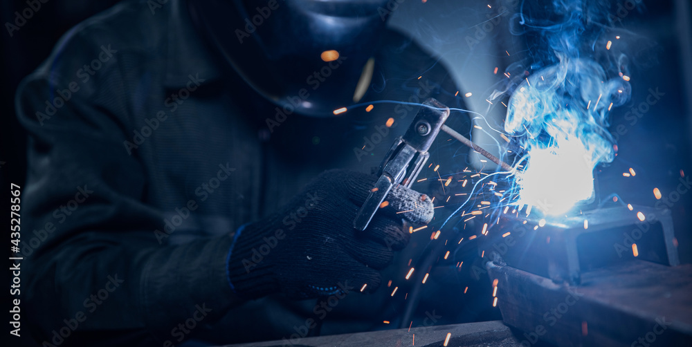 Professional welder performs work with metal parts in factory, sparks and electricity. Industry worker banner - obrazy, fototapety, plakaty 