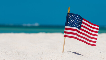 American Flag on the Beach. 4th of July Independence Day. US starry striped patriotic symbol. United States Holidays. Summer vacations. Ocean sand. Bright sunny day and blue color of sea salt water. 