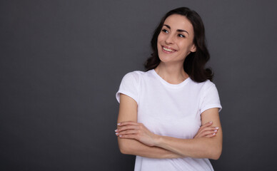 Young beautiful stylish happy woman in a white t-shirt is posing on the gray background