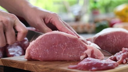 Wall Mural - Hand slicing fresh raw meat on a cutting board in the kitchen - slow motion