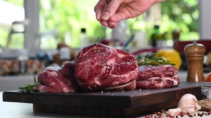 Canvas Print - Hand sprinkling salt on fresh raw beef meat on a cutting board