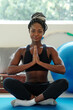 © DragonImages - Smiling beautiful fit young woman sitting in lotus position and keeping hands in namaste gesture