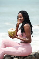 Wall Mural - Portrait of beautiful young woman in sportswear drinking coconut cocktail and smiling at camera