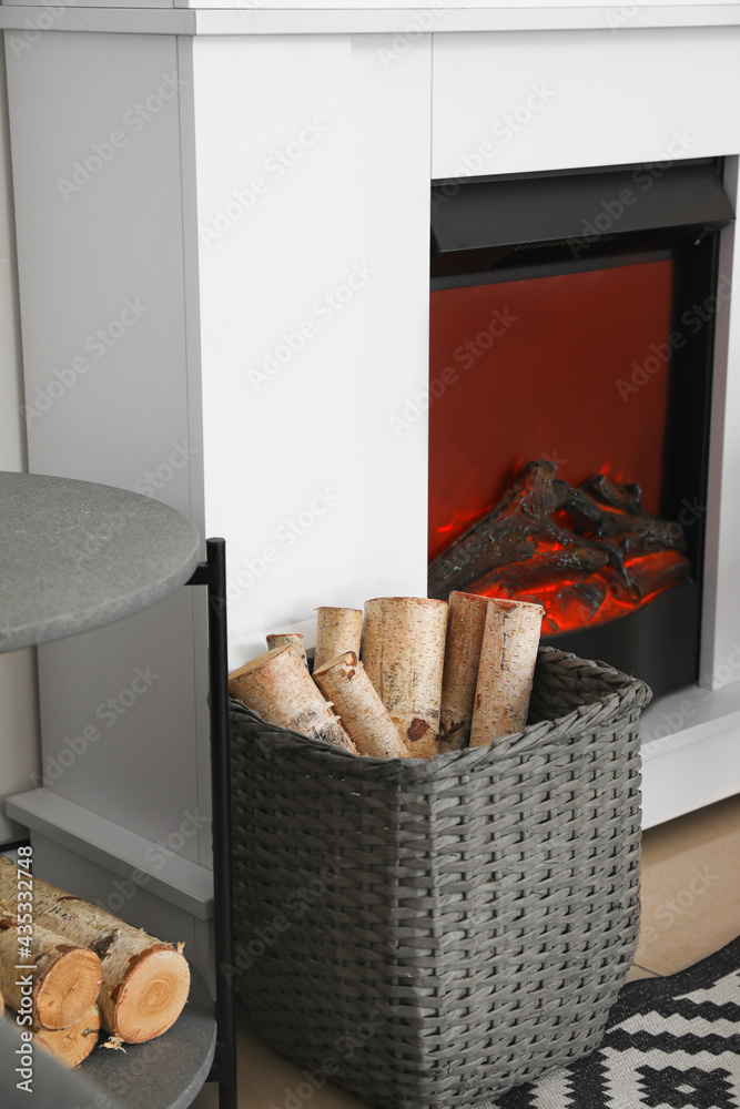 Basket with firewood near modern fireplace