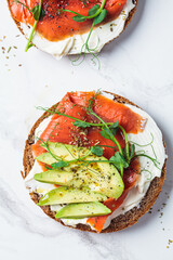 Wall Mural - Breakfast toast with cream cheese, salmon and avocado, white marble background.