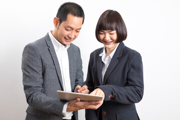 Businessman and woman holding tablet while discussing marketing plan standing on white background.