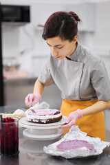 A bright pastry chef girl is engaged in the preparation of a cake