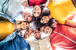 © Davide Angelini - Multiracial group of young people standing in circle and smiling at camera - Happy diverse friends having fun hugging together - Low angle view