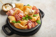 Italian aperitif with fried bread crescentine or gnocco fritto, mortadella and soft cheese, decorated with basil leaves. Traditional Bologna appetizer. Light background.