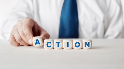 Wall Mural - Businessman pressing his finger on the wooden cubes with the word action. Taking action or action plan in business