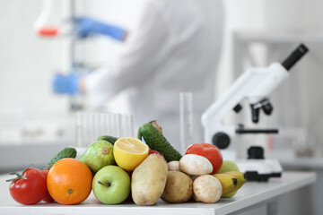 Wall Mural - fresh vegetables, fruits on table and scientist proceeding quality control in laboratory