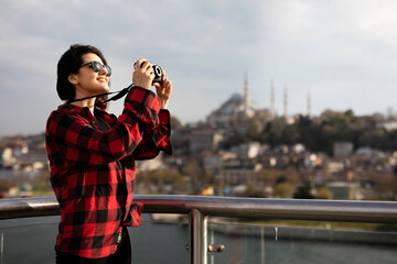 Young woman tourist standing with photo camera on the bridge. Beautiful woman traveling around the city...