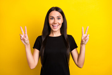 Photo of charming cheerful lady two hands fingers show v-sign toothy smile isolated on yellow color background