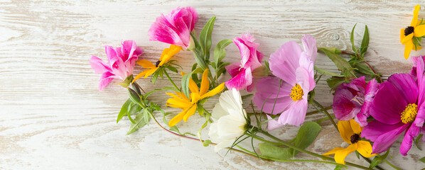 Wall Mural - composition of purple and yellow flowers on a light wooden background