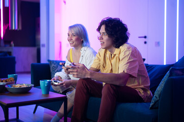 Wall Mural - Photo of young couple playing video games at home at night