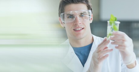 Poster - Composition of male scientist holding beaker with plant in laboratory with green motion blur