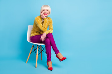 full length photo of positive short hairdo aged lady sit wear blouse pants isolated on blue color ba