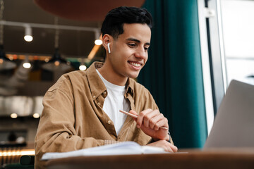 Sticker - Young hispanic man student sitting at the cafe table indoors