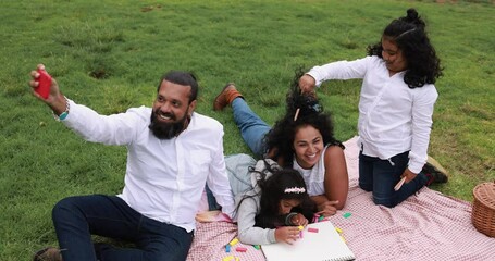 Wall Mural - happy indian family having fun at city park taking a selfie and laughing together - parents and chil