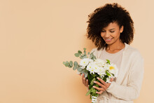 African American Woman Holding Bouquet Of Daisies And Smiling On Beige Background