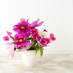 Wall Mural - vase with purple cosmos flowers on a light table, space for text