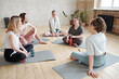 © pressmaster - Yoga trainer and group of active females interacting at break after training