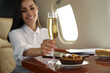 © New Africa - Woman with glass of champagne at table in airplane during flight, focus on hand