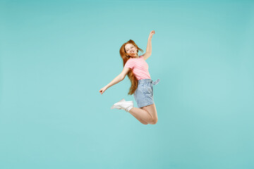 Wall Mural - Full length little funny overjoyed happy redhead kid girl 12-13 year old in pink t-shirt with outstretched hands arms isolated on pastel blue background studio Children lifestyle childhood concept