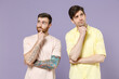 Two young thoughtful pensive wistful men friends together in casual t-shirt tattoo translate fun prop up chin look aside isolated on purple color background studio portrait People lifestyle concept