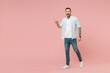 © ViDi Studio - Full length young happy smiling caucasian unshaven man 20s in blue striped shirt point index finger aside on workspace area isolated on pastel pink color background studio. People lifestyle concept.