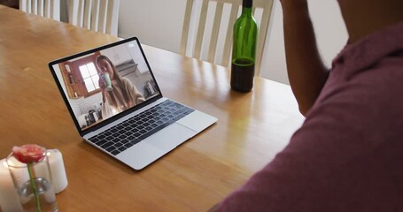 Poster - Mid section of african american man drinking wine while having a video call on laptop at home