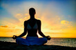 © TRAVEL EASY - Woman meditating, doing yoga, at the beach, sitting by the seashore, dressed in a white outfit at sunset