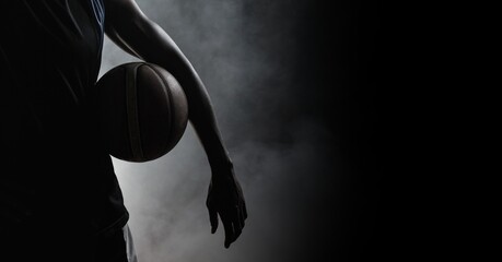 composition of athletic male basketball player over smoke on black background