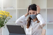 © amnaj - Asian businesswoman trussed irritated bored at the desk wearing a mask to prevent germs.