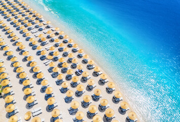 Aerial view of sea, empty sandy beach with sunbeds and umbrellas at sunny day in summer. Blue lagoon in Oludeniz, Turkey. Tropical landscape with clear turquoise water, deck chairs. Travel and leisure