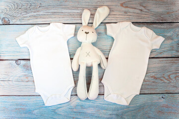 Layout Flat Put on a two white baby bodysuit on a wooden background with rabbit toy. Layout for design and placement of logos, advertising. Styled stock photography, stock photo. flat lay