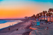 A Oceanside sunset at the beach draws people to it to walk and relax and the ocean shoreline.