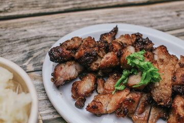 Wall Mural - Grilled Pork Neck with Spicy sauce and steamed sticky rice on rustic wooden table, Thai Food.