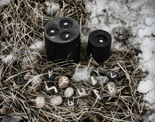 Wall Mural - Black candles and runes in grass and snow outside in winter.