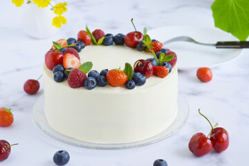 Top view on homemade vanilla cake decorated with berries: strawberries, blueberries, cherries, on marble background. Celebration cake. Summer dessert with berries. Delicious homemade summer cake