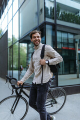 Wall Mural - Young stylish businessman going to work by bike in the city