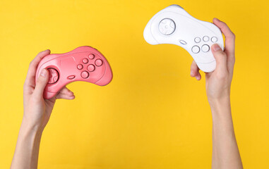 Canvas Print - Female hands hold retro gempads on yellow background. Gaming concept