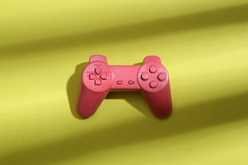 Wall Mural - Pink gamepad on a green background with trendy striped shadow. Minimalism. Abstraction. Concept art