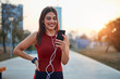 © astrosystem - Modern young woman with cellphone making pause during jogging exercise.