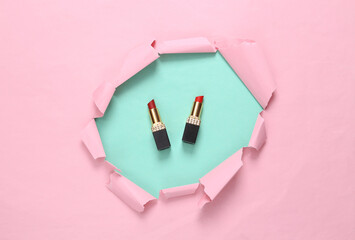 Wall Mural - Lipsticks on a pink background with a torn hole. Minimalism beauty still life. Creative layout