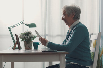 Wall Mural - Happy senior woman looking at her old pictures