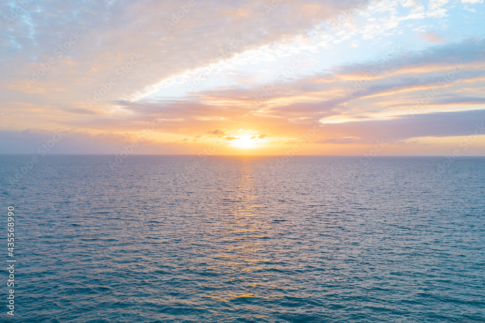 Calm sea with sunset sky and sun through the clouds over. Ocean and sky ...