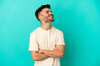 © luismolinero - Young caucasian man isolated on blue background looking up while smiling