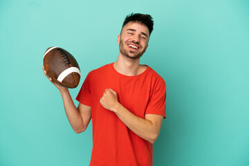 Wall Mural - Young Caucasian man playing rugby isolated on blue background celebrating a victory